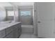 Well-lit bathroom features dual sinks, tile backsplash, modern fixtures, and a large window over the tub at 2460 Reading Trl, Kissimmee, FL 34746