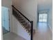 Inviting entryway with a staircase featuring dark wood railings, carpeted steps, and tile flooring at 2460 Reading Trl, Kissimmee, FL 34746