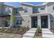 Modern townhome featuring a gray facade with a landscaped front yard and decorative stone accents around the entryway at 2460 Reading Trl, Kissimmee, FL 34746
