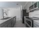 Bright kitchen with stainless steel appliances, gray cabinets, a spacious island, and a tiled backsplash at 2460 Reading Trl, Kissimmee, FL 34746