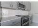Modern kitchen with stainless steel oven and cooktop, white backsplash, and gray cabinetry at 2460 Reading Trl, Kissimmee, FL 34746