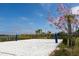 Beach volleyball court with fine sand, net, and pink flowering tree creating a scenic recreational space at 2460 Reading Trl, Kissimmee, FL 34746