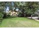 Well-manicured backyard with an iron fence, mature trees, and a screened-in pool enclosure at 2890 Wild Ginger Ct, Winter Park, FL 32792