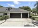 Three-car garage with black doors and a concrete driveway at 2890 Wild Ginger Ct, Winter Park, FL 32792