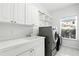 Bright laundry room with modern washer and dryer, storage cabinets, and utility sink at 2890 Wild Ginger Ct, Winter Park, FL 32792