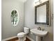 Charming powder room with a pedestal sink, decorative mirror, and an oval window at 2890 Wild Ginger Ct, Winter Park, FL 32792
