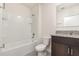 Bright bathroom with white tiled tub, toilet, dark cabinets, granite countertop, and modern sink at 3110 Areca Ave, New Smyrna Beach, FL 32168