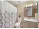 Well-lit bathroom with floral shower curtain, vanity, and decorative mirror at 3313 Buckland St, Deltona, FL 32738