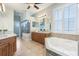 Elegant bathroom featuring double vanities, a soaking tub, a walk-in shower, and a window for natural light at 3531 Oriskany Dr, Orlando, FL 32820