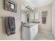 Bright bathroom featuring a white vanity, granite countertop, decorative mirrors, and modern lighting at 3531 Reston Dr, The Villages, FL 32162