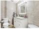 Bathroom with beige tiled walls and a vanity with granite countertop and decorative mirror at 8801 Crayson Ct, Kissimmee, FL 34747