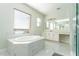 Bright bathroom featuring soaking tub, large mirror and vanity with marble floors and countertops at 10427 Royal Cypress Way, Orlando, FL 32836