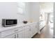 White kitchen with long counters, stainless steel microwave, and hardwood floors at 10427 Royal Cypress Way, Orlando, FL 32836