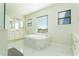 Luxurious bathroom featuring an oversized soaking tub, large windows, and bright white finishes at 10427 Royal Cypress Way, Orlando, FL 32836