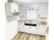 View of a kitchen with white cabinets, a sink, stainless range hood and light wood-look flooring at 1403 N Fern Creek Ave, Orlando, FL 32803
