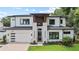 Elegant two-story home boasts a modern design, complete with a brick driveway, lush lawn, and attached garage at 1620 S Eola Dr, Orlando, FL 32806