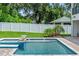 Backyard pool and spa featuring tiered tilework and elegant fire bowls, with a white fence at 1620 S Eola Dr, Orlando, FL 32806