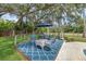 Relaxing outdoor patio with shade umbrella and furniture is nestled next to an inground pool under mossy trees at 223 Royal Oaks Cir, Longwood, FL 32779
