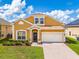 Charming two-story home with a well-kept lawn, brick walkway, and a two-car garage at 233 Cadiz Loop, Davenport, FL 33837