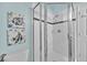 Modern walk-in shower with chrome frame and fixtures, white tile and decorative artwork on the wall at 233 Cadiz Loop, Davenport, FL 33837