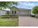 Charming home featuring a stone facade, brick driveway, manicured lawn, and a two-car garage at 2829 Red Alder Blvd, Ocoee, FL 34761