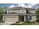 Charming two-story home with neutral siding, well-maintained lawn, and two car garage at 313 Cornerstone Dr, Groveland, FL 34736