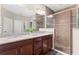 Well-lit bathroom featuring granite countertop vanities and a glass shower enclosure with brown tiles at 337 Meadow Pointe Dr, Haines City, FL 33844