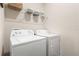 Efficient laundry area with white washer and dryer units, enhanced by shelving for storage at 337 Meadow Pointe Dr, Haines City, FL 33844