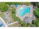 An aerial view of the community pool surrounded by sun loungers, palm trees, green space, and walking paths at 4443 Brook Hollow Cir # 19A, Winter Springs, FL 32708