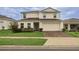 Two-story home featuring a paver driveway, lush landscaping, and a well-manicured lawn at 565 Ogelthorpe Dr, Davenport, FL 33897