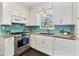 Modern kitchen featuring stainless steel appliances, granite countertops, tile backsplash, and bright white cabinetry at 600 Sheridan Blvd, Orlando, FL 32804