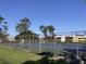 Community tennis courts, visible behind a chain-link fence, with tall pine trees in the background at 6013 Scotchwood Gln # 20, Orlando, FL 32822