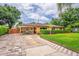 Charming single-story home featuring a manicured lawn, brick driveway, and a welcoming covered entryway at 6430 Yellowstone St, Orlando, FL 32807