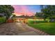 Charming single-story home featuring a manicured lawn, brick driveway, and a welcoming covered entryway at dusk at 6430 Yellowstone St, Orlando, FL 32807