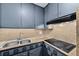 Compact kitchen features gray cabinets, stone countertops, stainless steel sink, and a black glass cooktop at 6430 Yellowstone St, Orlando, FL 32807