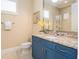 Bathroom features a vanity with granite countertop, framed mirror, and blue cabinets at 7398 Gathering Ct, Reunion, FL 34747