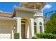 Close-up of the front entrance of this charming home with a tile roof and landscaped garden at 7398 Gathering Ct, Reunion, FL 34747