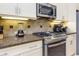 Modern kitchen featuring stainless steel appliances, granite countertops, and cream colored cabinets at 7398 Gathering Ct, Reunion, FL 34747