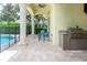 Covered outdoor patio area with view of the pool and travertine floors at 7398 Gathering Ct, Reunion, FL 34747