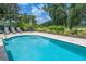 Gorgeous backyard pool and patio with lush green landscaping and travertine pavers at 7398 Gathering Ct, Reunion, FL 34747