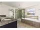 Bright bathroom features a granite countertop, glass shower, and soaking tub under a large window at 7816 Winter Wren St, Winter Garden, FL 34787