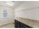 Well-lit laundry room with granite countertops, black cabinets and a metal shelf at 7816 Winter Wren St, Winter Garden, FL 34787