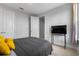 Well-lit bedroom featuring carpet, gray comforter with yellow pillows, and a television on a stand at 8427 Modiano St, Orlando, FL 32827