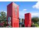 Two tall, vibrant red buildings constructed from shipping containers, part of Boxi Park, against a clear blue sky at 8427 Modiano St, Orlando, FL 32827