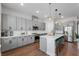A well-equipped kitchen with gray cabinets, steel appliances, an island with a quartz countertop, and modern lighting at 8427 Modiano St, Orlando, FL 32827
