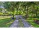 Gated entrance featuring a gravel driveway leading into the property surrounded by trees at 2508 Fawn Run, Oviedo, FL 32765