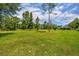 View of a home lot with grass, mature trees, and a barn in the background at 2508 Fawn Run, Oviedo, FL 32765