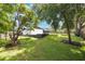 A spacious backyard with a white brick house, a dark pergola, and lush green grass at 102 Linda Ln, Lake Mary, FL 32746