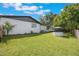 A large, verdant backyard featuring a white brick house, a wishing well, and abundant green space at 102 Linda Ln, Lake Mary, FL 32746