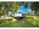 A spacious backyard with a white brick house, a dark pergola, and lush green grass at 102 Linda Ln, Lake Mary, FL 32746